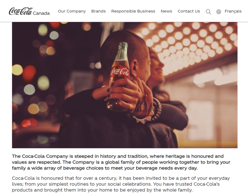 Screenshot from Coca-Cola Canada's website showing a warm image of a smiling woman with her arms around a man, Coke bottle in hand, with lights in the background.
