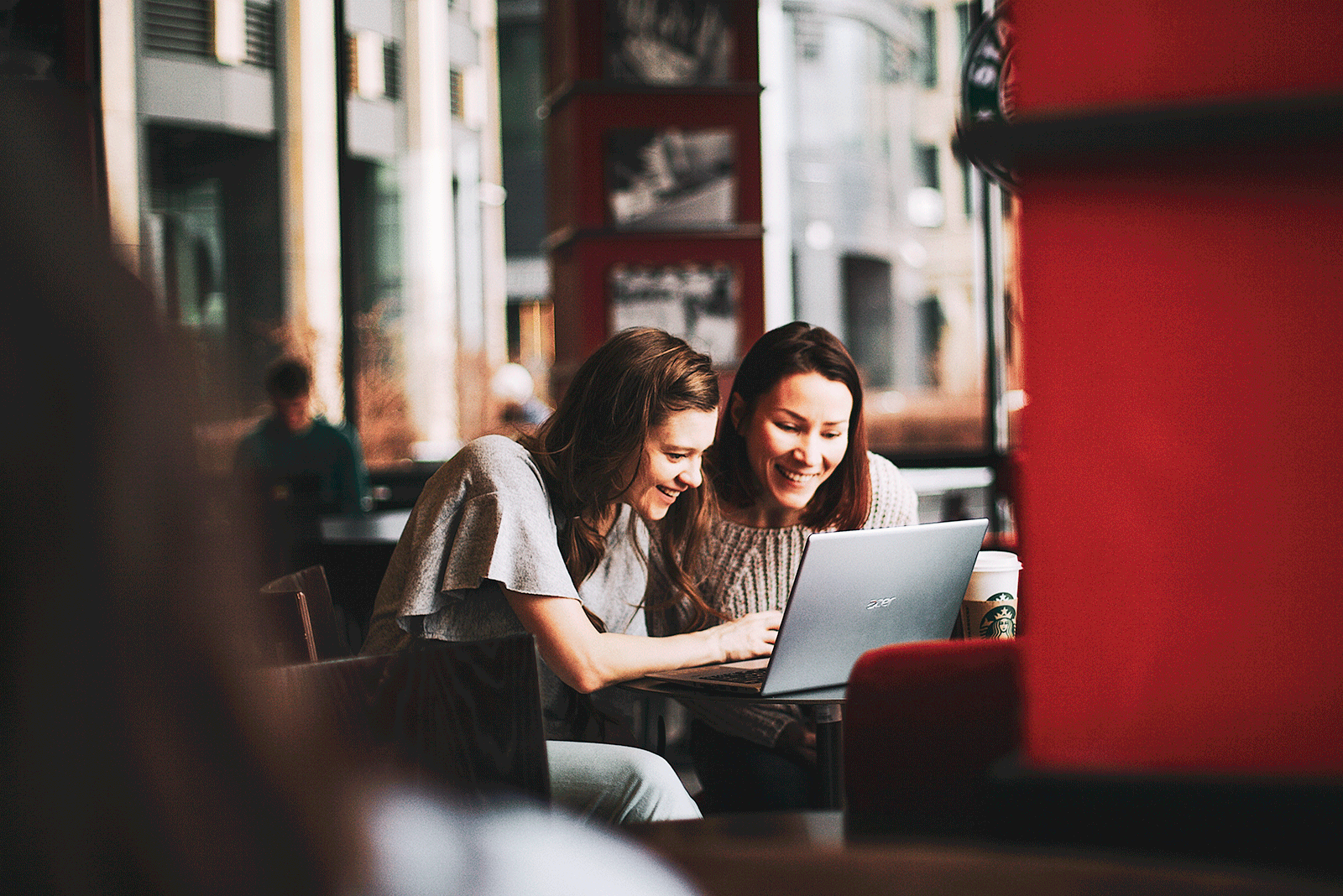 Two women sitting at a table looking at a laptop screen